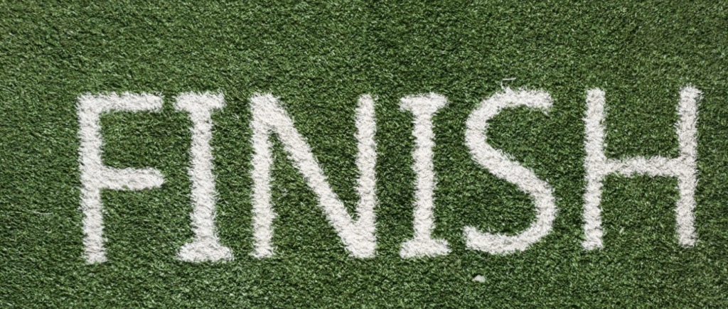 An image of a finish line - the word "FINISH" painted on the grass or astroturf of a field.